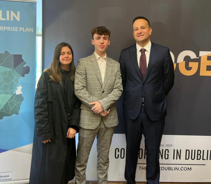 Dylan Corrigan standing between a woman and former Taoiseach Leo Varadkar in front of event banners